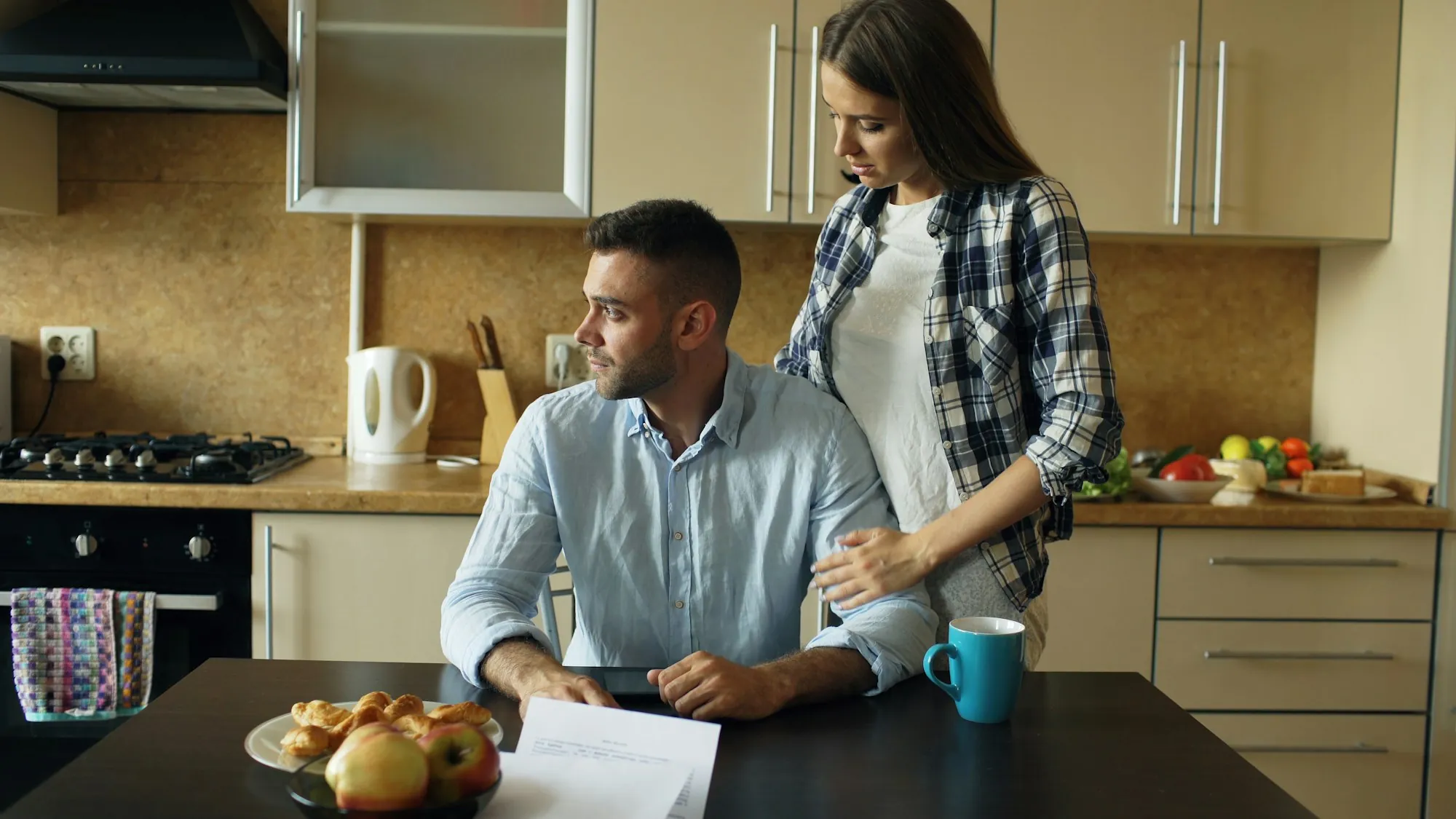 Two people talking over coffee at a kitchen table