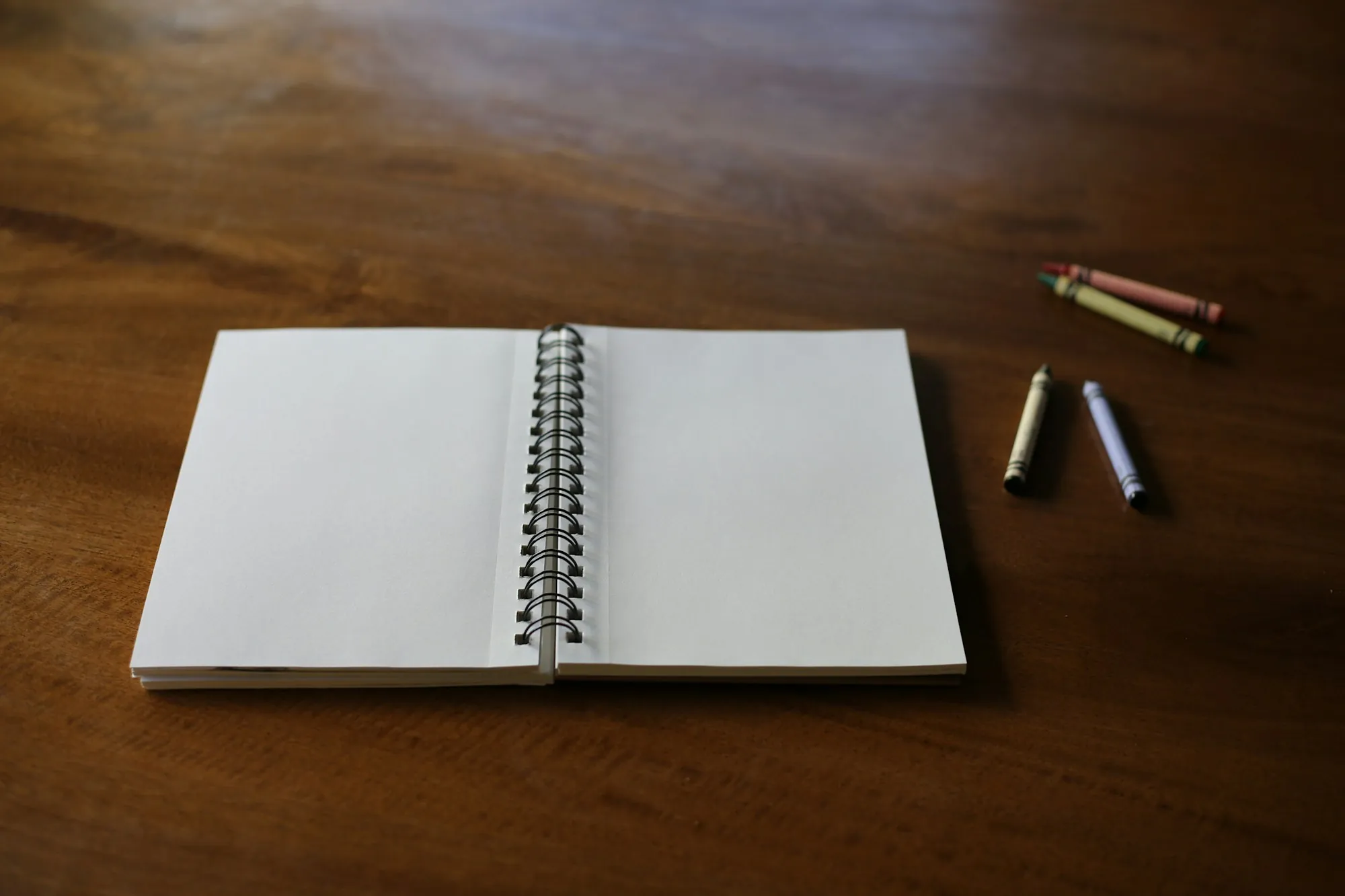 An open notebook with a pen and pencils on a desk