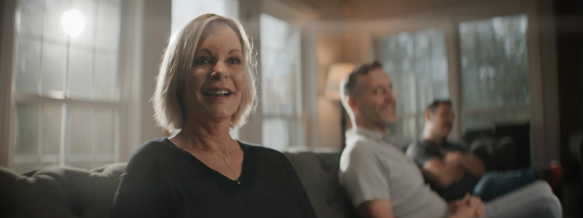 A smiling woman sitting on a sofa with others